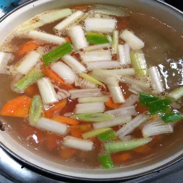 Haluskan bawang putih kemudian tumis hingga harum dan matang.
Masukkan ke dalam rebusan ayam, tambahkan daun bawang.