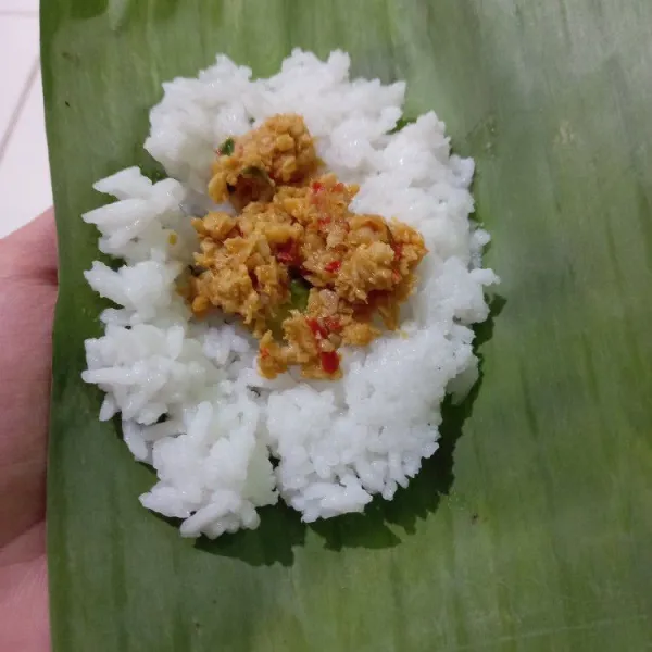 Siapkan daun pisang, ambil nasi 2 sdm, beri sambal tempe di tengahnya, lalu tutup dan lipat daun pisang.