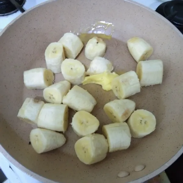 Tuang margarin pada teflon, nyalakan api sedang. Masukkan potongan pisang.