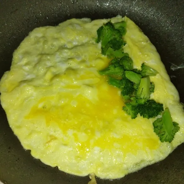 Lalu tata brokoli di salah satu sisinya, jika bagian bawah sudah mulai matang, gulung perlahan, lalu sisakan sedikit ujung telur dadar lalu geser ke pinggir wajan.