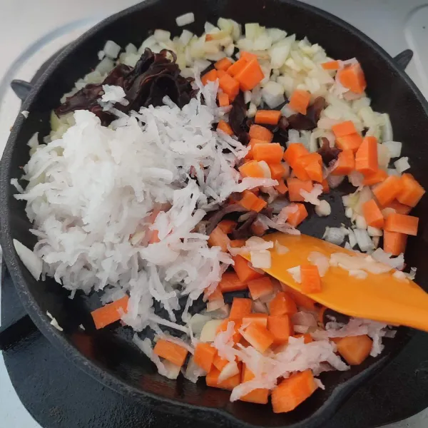 Masukkan wortel, lobak putih dan jamur kuping, aduk rata. Tumis sampai layu.