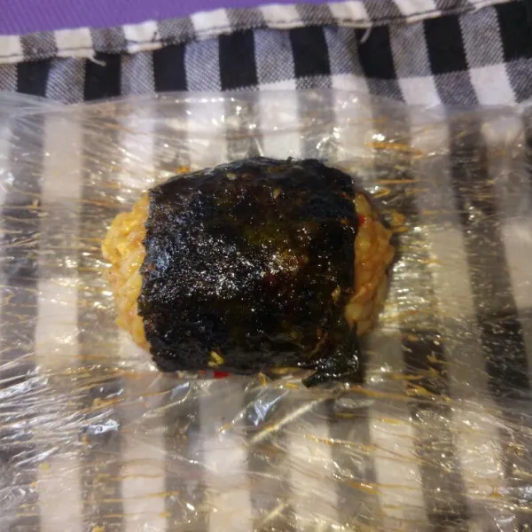 Selagi hangat, bentuk nasi goreng sesuai selera lalu balut dengan nori, lakukan sampai habis dan sajikan untuk sarapan atau bekal anak.