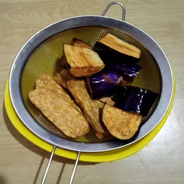 Potong-potong terong dan tempe, lalu goreng, kemudian tiriskan.