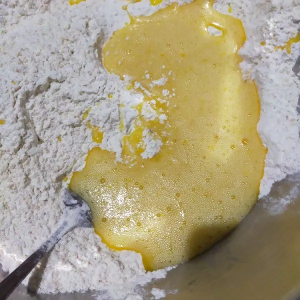 Masukkan kocokan gula dan telur ke dalam campuran tepung, lalu aduk rata.