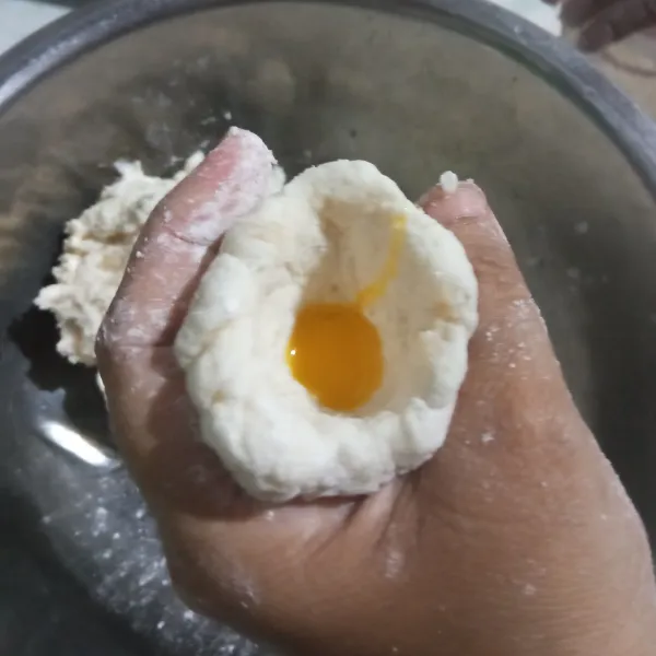 Baluri tangan dengan tepung sagu, ambil adonan sebesar bola pimpong, kurang lebih 45 gram. Bentuk bulat dan lubangi bagian atas dengan bantuan jempol lalu bentuk seeperti mangkok (mangkuknya agak dalam ya, jadi agak lonjong). Masukkan 1 sdm kocokan telur rapatkan bagian atas dan langsung direbus/ masukkan ke dalamm panci, pastikan air sudah mendidih. Untuk isian pempek saya memakai 1 butir telur dengan 1 kuning telur (putihnya dimasukan di adonan).