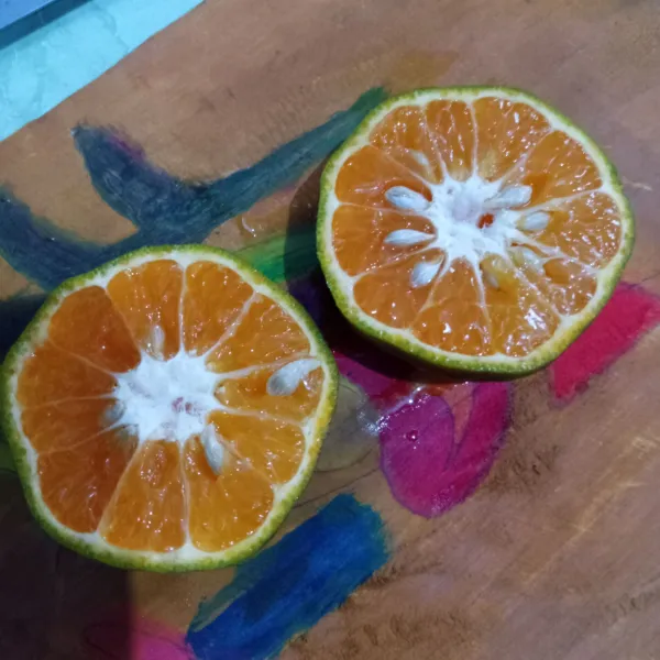 Siapkan buah jeruk, lalu belah dua.