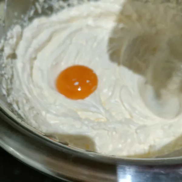 Turunkan mixer kecepatan rendah, masukkan kuning telur secara bertahap. Mixer hingga tercampur rata, lalu sisihkan.
