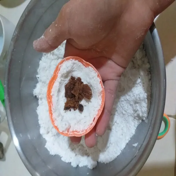 Masukkan tepung ke cetakan, letakkan gula merah diatasnya.