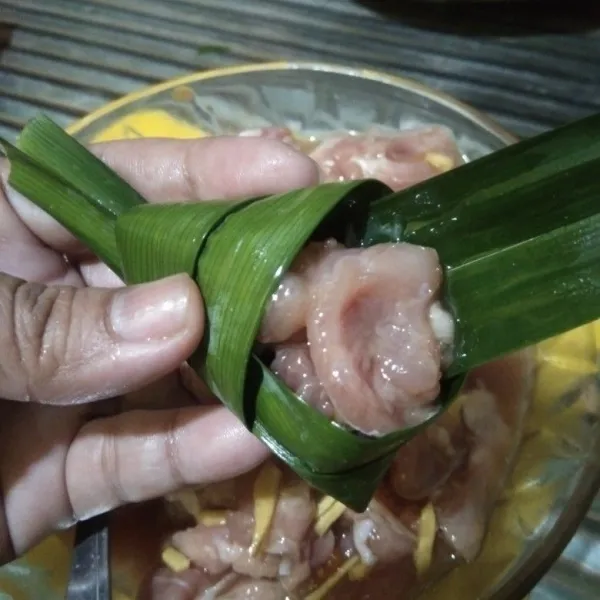 Keluarkan marinasi ayam dari chiller, kemudian masukkan potongan ayam ke dalam daun pandan. Kedua ujung daun pandan selipkan di belakangnya. Lakukan berulang sehingga marinasi ayam habis.