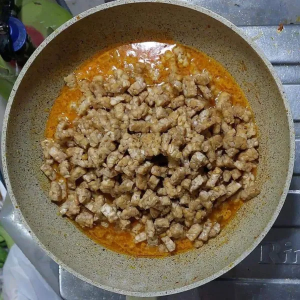 Tambahkan air masak sampai mendidih, masukkan tempe goreng.