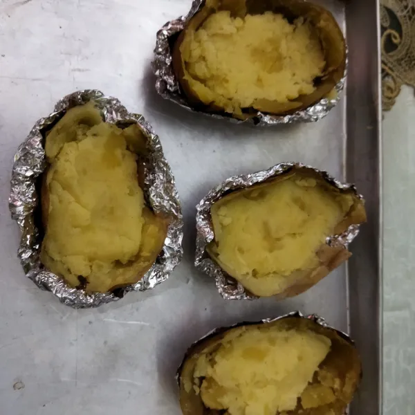 Letakkan kulit kentang pada aluminium foil, isi dengan kentang tumbuk.