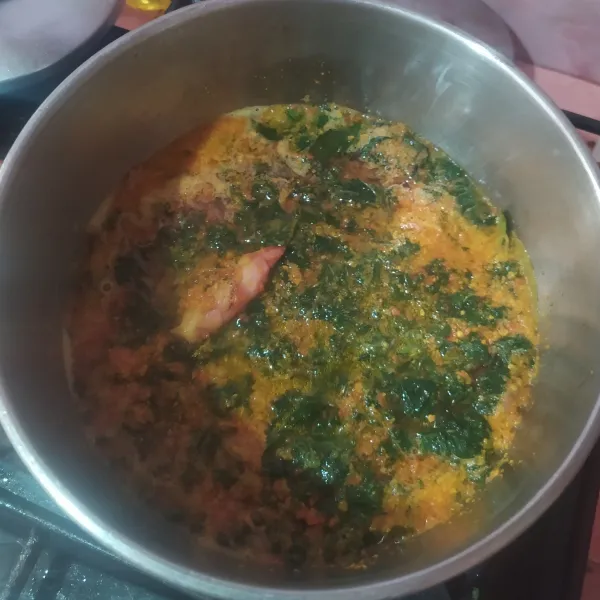 Didihkan air di panci, lalu masukkan daun singkong dan bumbu yang sudah di tumis. Aduk rata.
