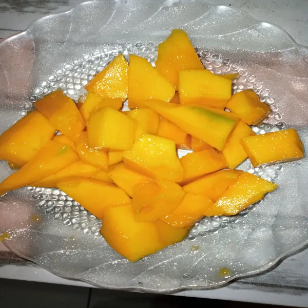 Kupas mangga lalu bersihkan dan potong-potong mangga.