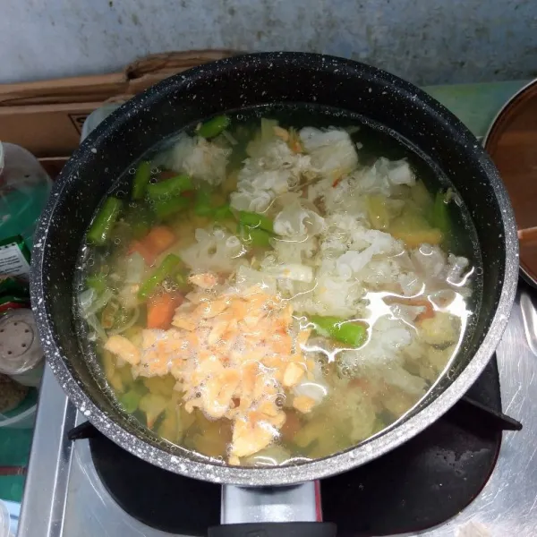 Masukkan jamur salju, bumbu tumis, bawang putih goreng, gula pasir, garam, dan lada bubuk ke dalam rebusan sayur. Masak sampai mendidih.