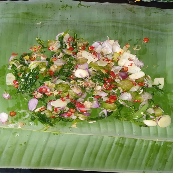 Siapkan 2 lembar daun pisang, ratakan 1/2 bumbu iris di atasnya.