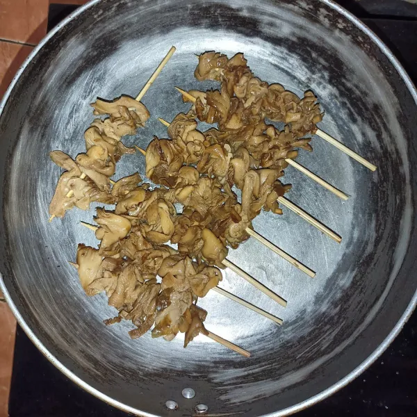 Tusuk jamur dengan tusuk sate, lalu panggang sampai kecokelatan dan aroma bakar keluar.