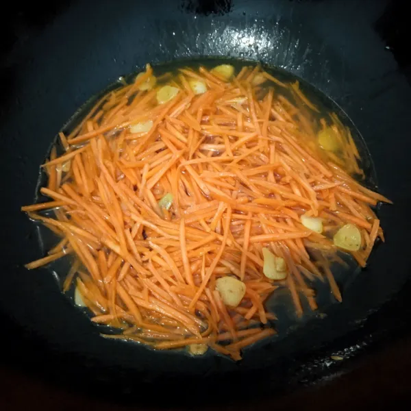 Tumis bawang putih sampai harum lalu masukkan wortel. Beri air secukupnya, aduk sebentar lalu tunggu wortel sampai agak layu.