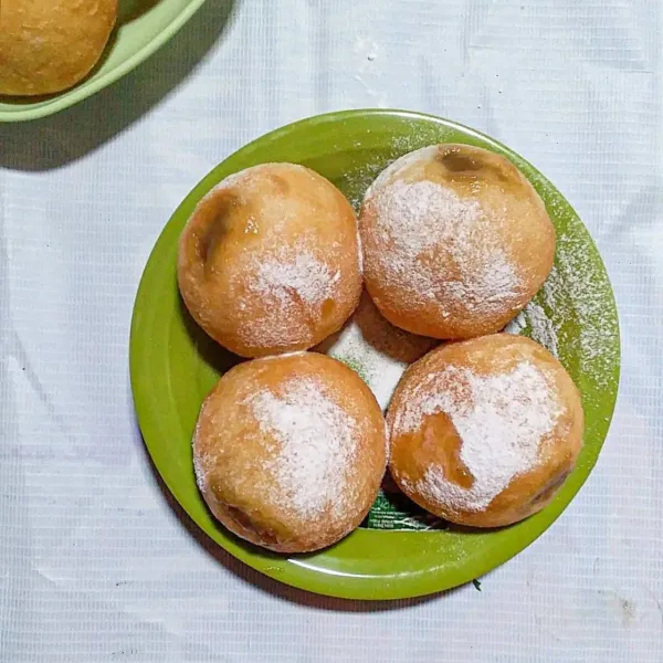 Tusuk bomboloni dengan sumpit. Semprotkan vla gula merah. Taburi gula halus. Kemudian sajikan.