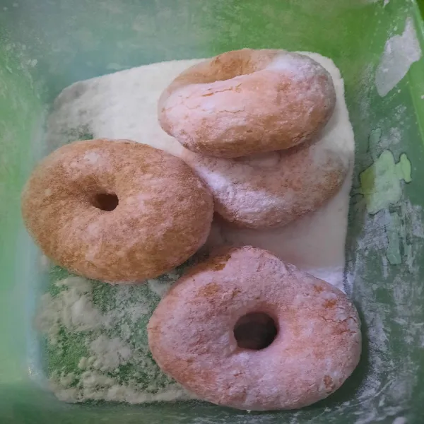 Taruh gula halus dalam wadah, lalu masukkan donut dan tutup wadah. Kemudian kocok agar gula menempel di donut, lalu siap disajikan.
