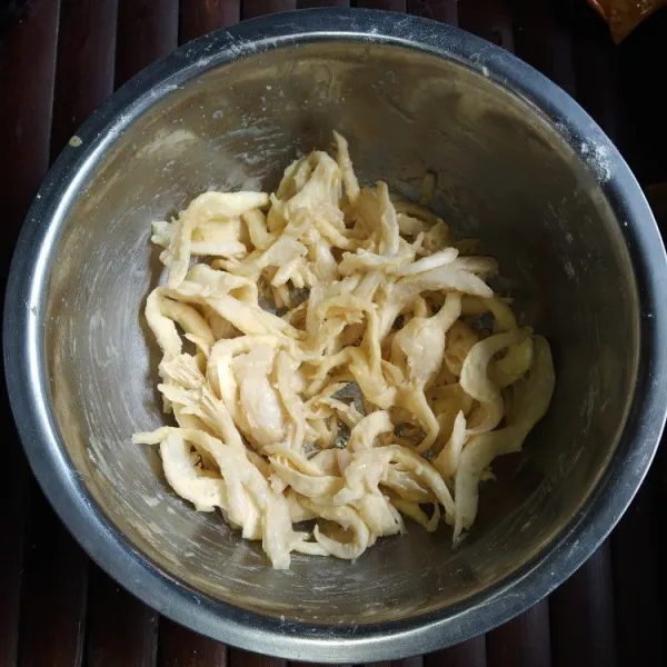 Suwir-suwir jamur tiram, lalu cuci bersih, kemudian peras. Tambahkan kaldu bubuk, saus tiram, telur, dan tepung beras, lalu aduk rata.