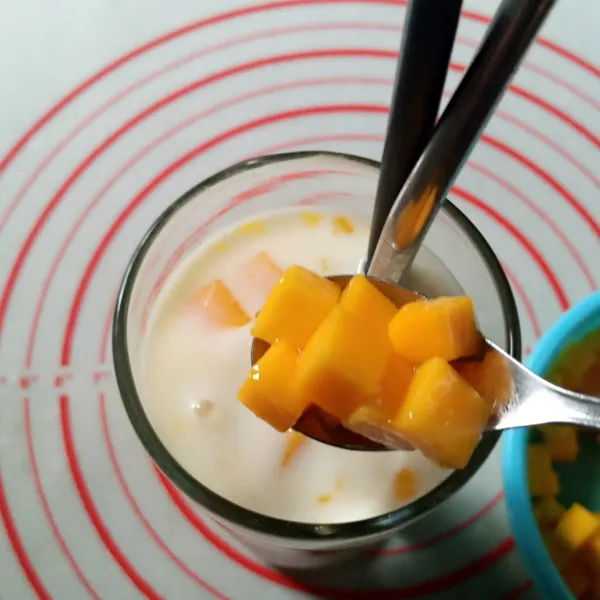 Tuang yakult masing-masing 1 botol, tambahkan potongan mangga sebagai topping dan es batu secukupnya. Sajikan.