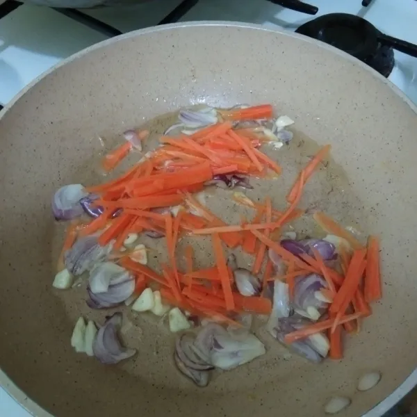 Tumis irisan bawang merah dan bawang putih hingga harum, lalu masukkan irisan wortel, aduk rata.