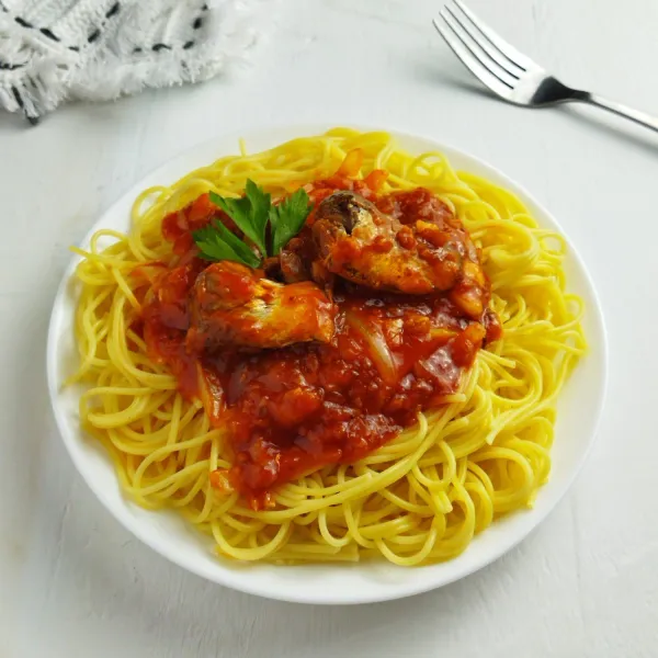 Tata spaghetti di piring saji, siram dengan saos sarden. Sajikan.