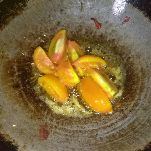 Potong-potong tomat, lalu goreng dengan api kecil, sambil menunggu cabe dan bawangnya sedang diulek.