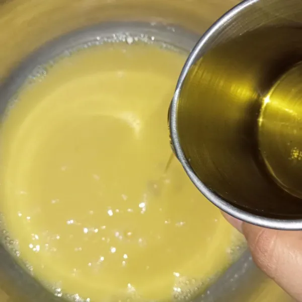 kocok kuning telur menggunakan whisk kemudian tuang susu cair dan minyak