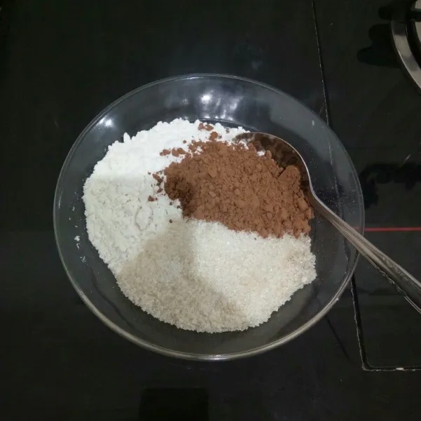 Campur tepung terigu, gula pasir, dan coklat bubuk di dalam mangkok. Aduk rata.