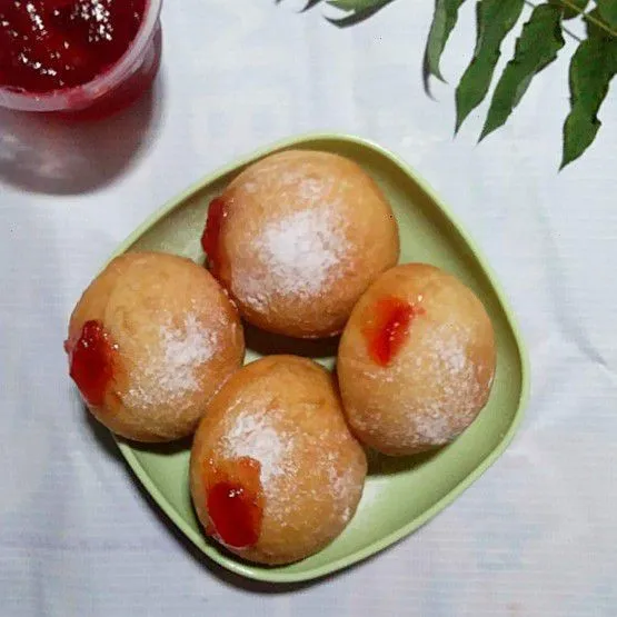 Masukan selai strawbery ke dalam piping bag lalu gunting ujungnya. Lubangi bomboloni dengan sumpit lalu isi selai strawbery. Taburi gula halus.