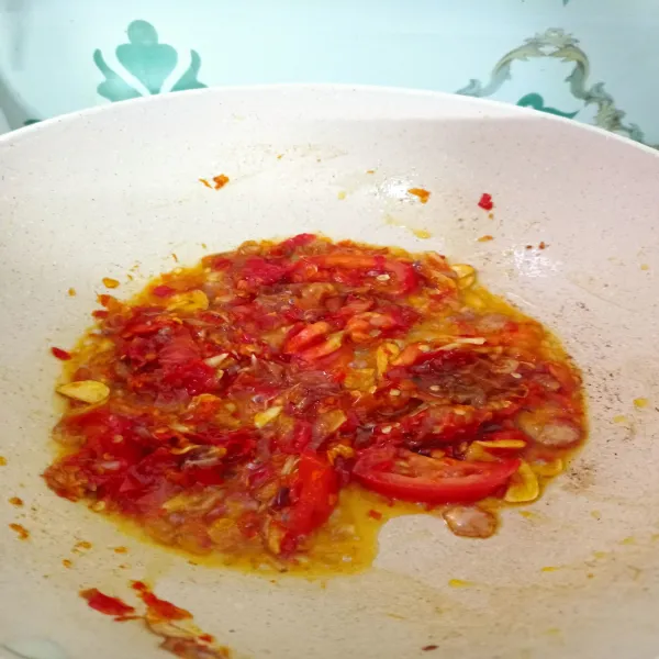 Tambahkan cabai yang telah dihaluskan dan tomat, aduk rata. Tumis hingga bau langu cabai hilang.