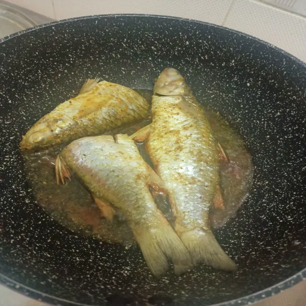 Lumuri ikan dengan bumbu racik ikan goreng, kemudian goreng ikan hingga matang.