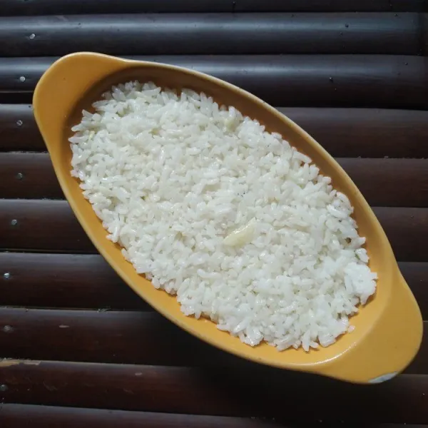 Masukkan nasi kedalam wadah tahan panas, padatkan.