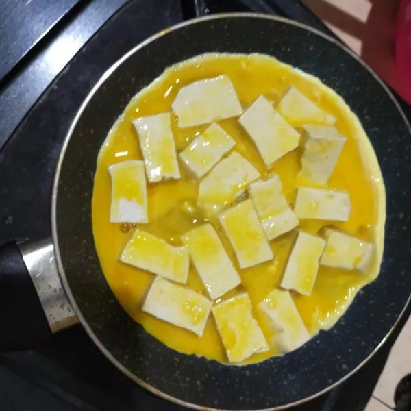 Panaskan wajan rata. Tuang adonan tahu telur, masak hingga bagian bawahnya matang kecoklatan.