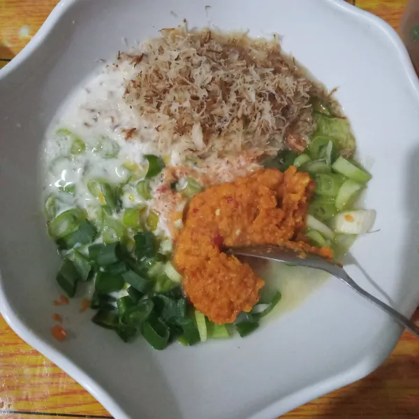 Campurkan telur kocok, larutan tepung, kelapa parut sangrai, tumisan bumbu, dan irisan daun bawang.