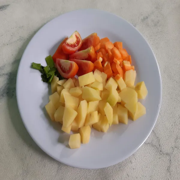 Potong dadu untuk wortel dan kentang, tomat dibagi 4.