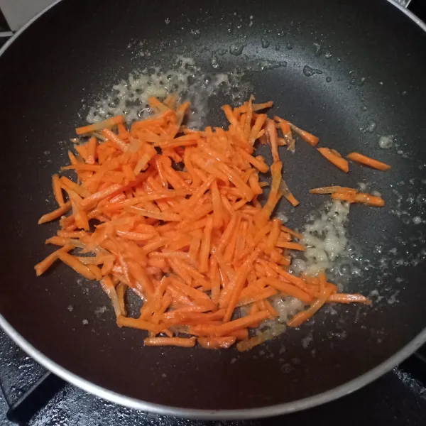 Tumis bawang putih sampai harum, lalu masukkan irisan wortel, aduk sampai layu.