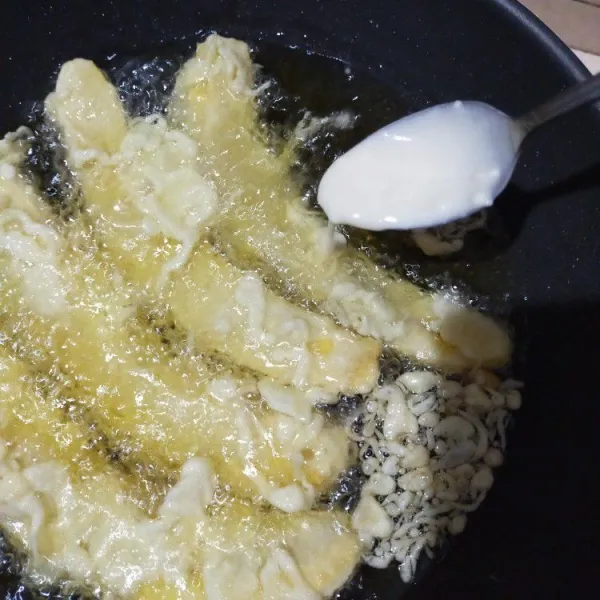 Lalu goreng di minyak yang sudah dipanaskan. Minyak harus cukup membuat pisang mengapung. Lalu beri tiap pisang topping tepung basah di seluruh permukaannya.