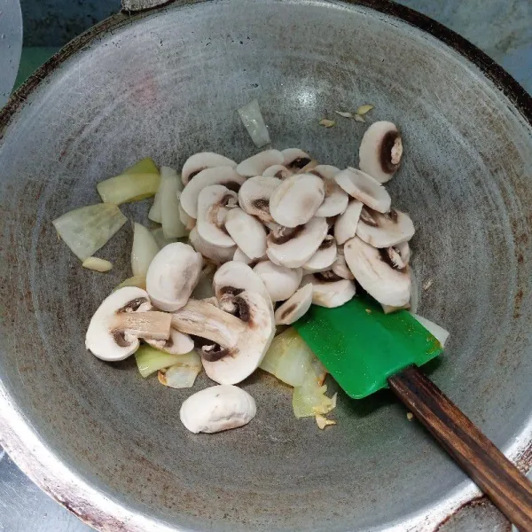 Tumis bawang bombai dan bawang putih sampai harum dan layu. Kemudian masukkan jamur kancing. Tumis sampai layu.