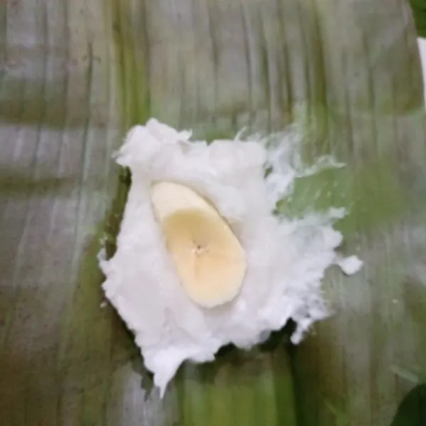 Ambil daun tuang sedikit adonan di atas nya selipkan irisan pisang tutup lagi dengan adonan bungkus dan lipat.