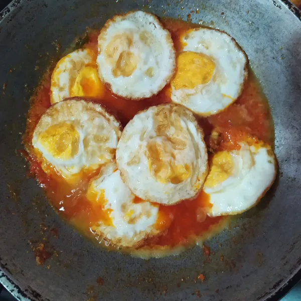 Masukkan air, lalu bumbui gula merah, kaldu bubuk, dan garam, lalu aduk rata. Masukkan telur ceplok, siram-siram hingga tercampur bumbu rata.