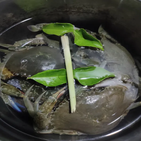 Rebus kepiting, tambahkan 1 batang serai dan 2 lembar daun jeruk, rebus hingga mendidih dan kepiting berubah warna lalu buang air rebusan.