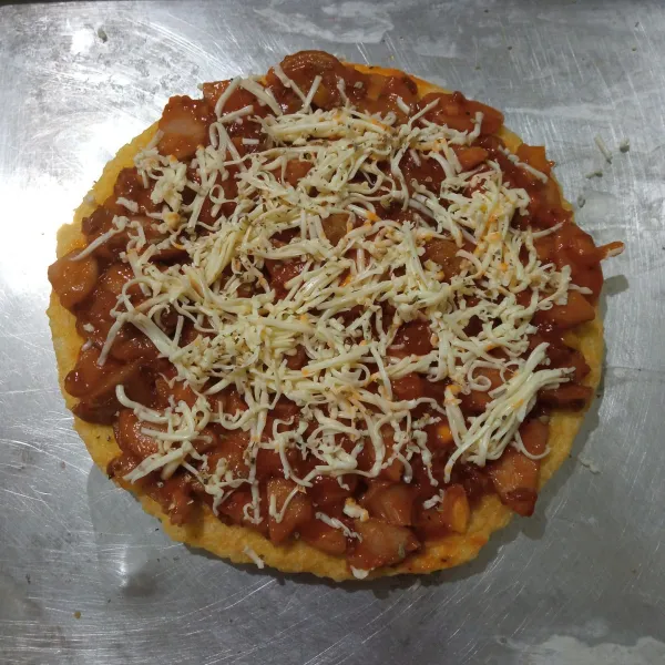 Letakkan pizza nasi di atas loyang yang sudah di olesi tipis margarin, lalu beri taburan keju.