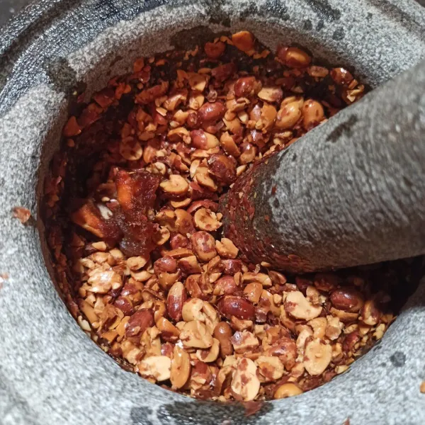 Hancurkan kacang tanah, kemudian beri asam jawa. Kemudian aduk rata sambil lalu dihancurkan.