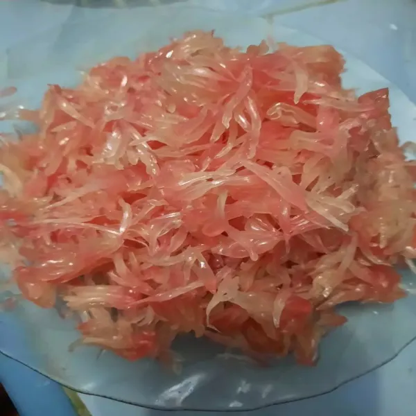 Kupas jeruk bali dari kulit tipisnya kemudian pisahkan bulirnya