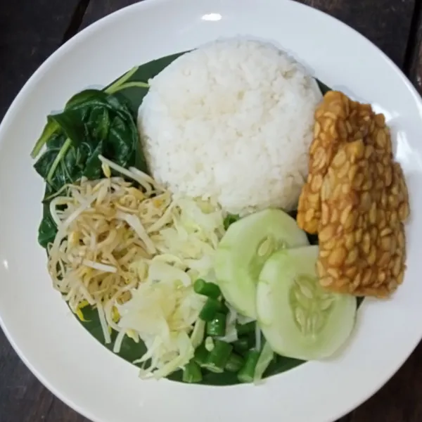 Tata nasi, sayuran, irisan timun dan lauk pauk.