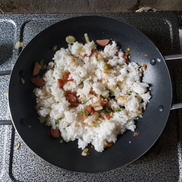 Kecilkan api, masukkan nasi putih, aduk hingga bumbu rata