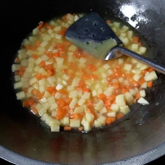 Masukkan wortel, kentang dan air. Masak hingga air menyusut.
