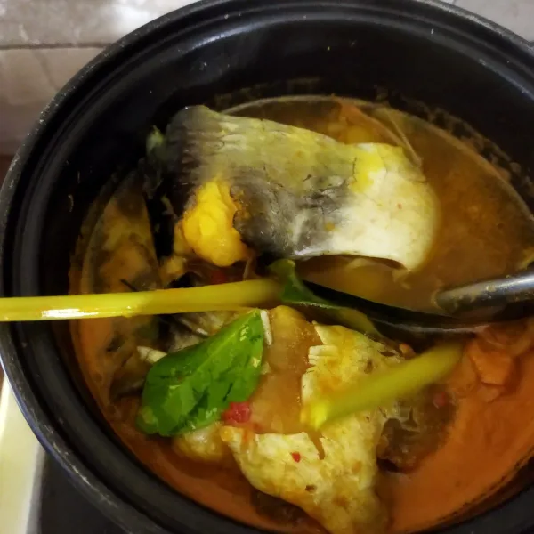 Masukkan ikan patin, sereh, daun salam, daun jeruk, dan lengkuas, kecilkan api, masak sampai ikan setengah matang.